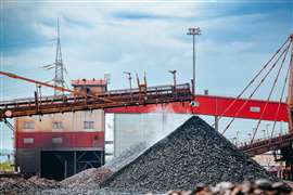 An excavator digs and loads hot briquetted iron into a heap. (Image: Adobe Stock)