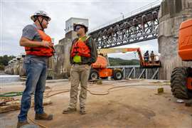 Contractors stand in front of the Montgomery locks and dam facility on the Ohio River, Pennsylvania, USA