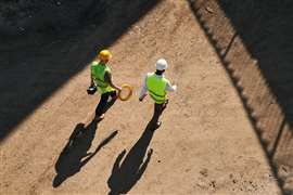 Directly above view of builders in hardhats and green waistcoats working at construction site